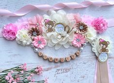 a bunch of flowers that are on top of a white table with pink ribbons and teddy bears