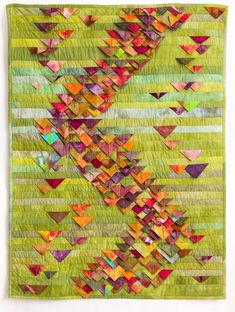 a green quilt with colorful triangles on it