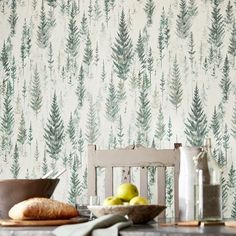 a wooden table topped with green apples next to a wallpaper