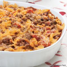 a casserole dish with meat and cheese in it sitting on a tablecloth