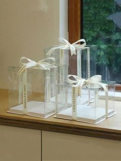 three clear boxes with white ribbons tied around them