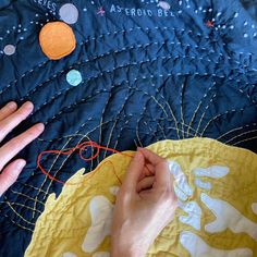 two hands are stitching together on a quilt