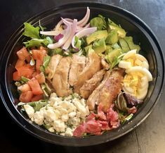 a black bowl filled with salad and meat