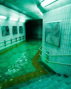 an empty bathroom with green floor and tile walls in the background, there are pictures hanging on the wall