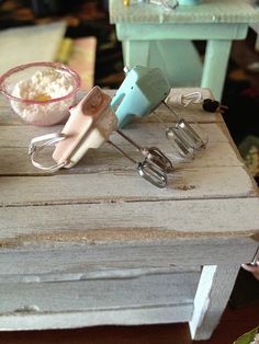 an old wooden table with various kitchen utensils on it and a bowl full of flour