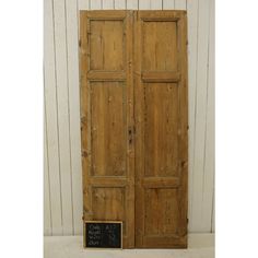 an old pair of wooden doors with chalkboard on the bottom and bottom, in front of a white wall