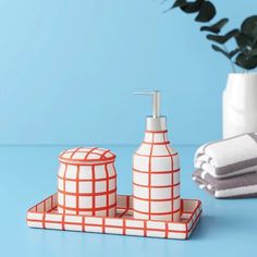 a white and red bathroom set sitting on top of a blue table next to a plant