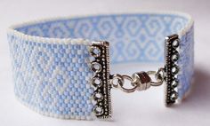 a blue and white bracelet with two silver chains on it's end, sitting on top of a white surface