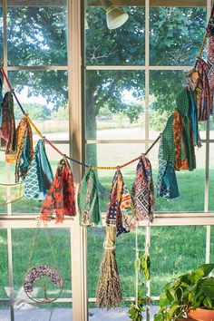 there are many scarves hanging on the window sill in front of the plants