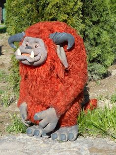 a stuffed animal that is sitting on the ground in front of some grass and bushes