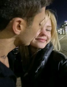 a man and woman standing next to each other on the street at night with their eyes closed