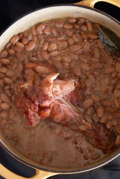 a pot filled with beans and meat on top of a stove