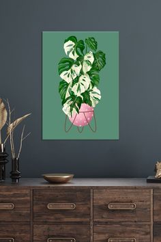 a painting of a house plant in a pink pot on a green wall above a dresser