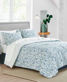 a bed with blue and white flowers on it in a room next to a window