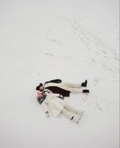 a man and woman laying in the snow on top of each other with their arms around each other