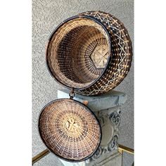 two woven baskets sitting on top of a stone pillar in front of a wall and stairs