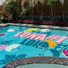 a pool decorated with flowers and the word hawaii spelled out in pink, yellow, and blue