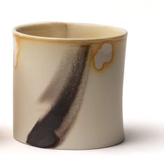 a white and brown cup sitting on top of a table next to a black object