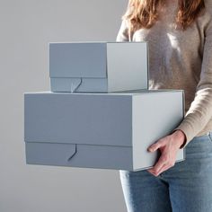 a woman is holding three boxes in her hands, both stacked on top of each other