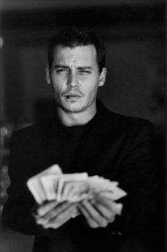 black and white photograph of a man holding stacks of cards in his hands while looking at the camera