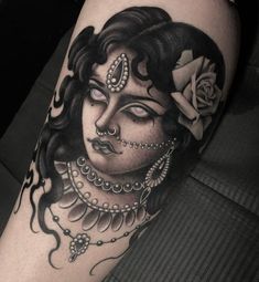 a black and white tattoo with a woman's face on her leg, holding a rose