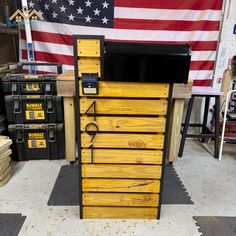 a large wooden cabinet sitting on top of a floor next to a flag and other tools