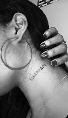 a woman with a small tattoo on her neck and behind her ear is a hoop