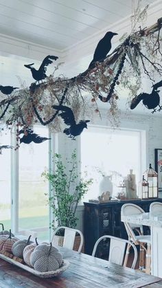 a wooden table topped with lots of birds hanging from it's branches in front of a window