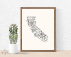 an art print of the state of california on a wall next to a potted cactus