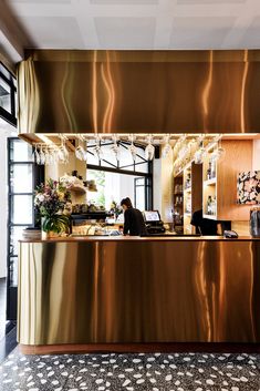 a person sitting at a desk in front of a large mirror with gold foil on it