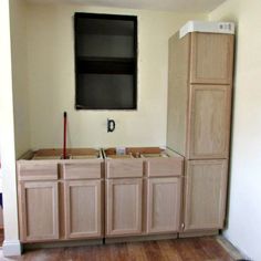 an empty kitchen with unfinished cabinets and a flat screen tv mounted above the cabinet doors