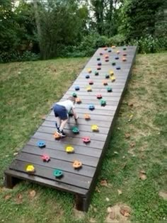 a child playing with toys on an outdoor play structure in the grass near some trees