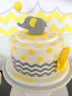 a baby elephant on top of a yellow and gray cake with white polka dot trim