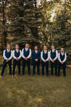 Groomsmen standing with hands crossed in blue suit and tux Navy Blue And Cream Groomsmen Suits, Groom In Suit Groomsmen In Vest, Navy Vest Khaki Pants Groom Attire, Groomsmen Attire April Wedding, Trending Groomsmen Attire, Male Wedding Party Attire, Navy Blue Groomsman Suit, Navy Suit With Vest Wedding, Groomsmen With Vests Only