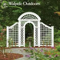 a white arbor in the middle of a garden with purple flowers and trees around it