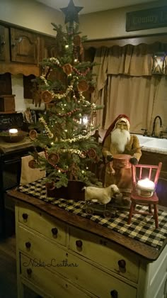 a small christmas tree in the middle of a kitchen with a santa clause sitting on it