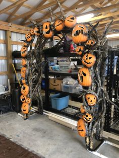 an arch made out of branches with pumpkins on it in a garage area,