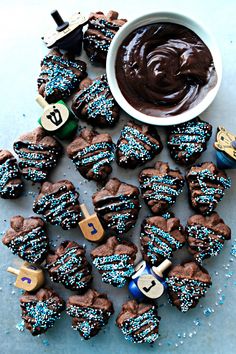 chocolate cookies with blue and white sprinkles next to a bowl of chocolate frosting