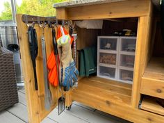 an outdoor kitchen with utensils hanging on the wall and storage bins below