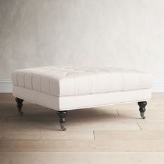 a white bench sitting on top of a hard wood floor in front of a wall