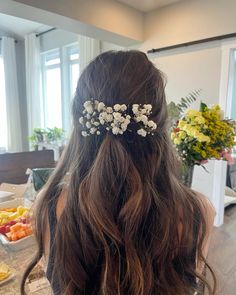 the back of a woman's head with flowers in her hair, sitting on a table