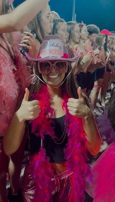 a group of women dressed in pink and black posing for the camera with their thumbs up