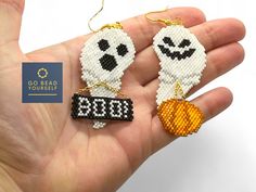 someone is holding two beaded ghost earrings in their hand