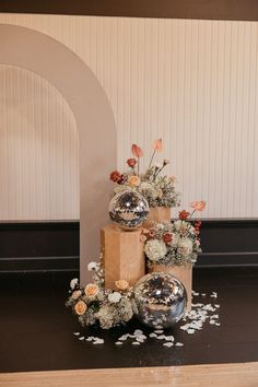 three vases with flowers are stacked on top of each other in front of an arch