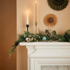 a mantel decorated with candles and greenery