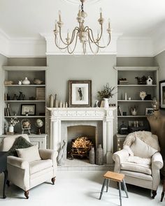 a living room filled with furniture and a fire place under a chandelier in front of a fireplace