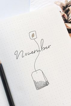 an open notebook with the word november written on it next to a pencil and plant