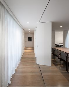 an empty room with white walls and wooden flooring, along with long tables and chairs