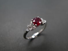 a red and white diamond ring on a black surface