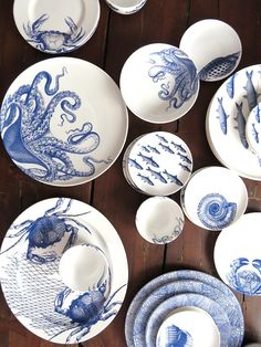 an assortment of blue and white plates on a wooden table, with octopuses painted on them